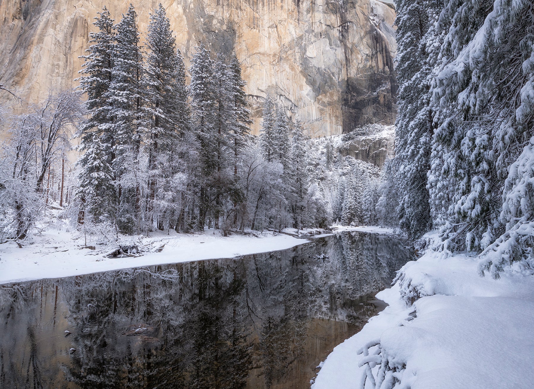 Snow-covered trees and mountains reflected in a calm lake by Franka Gabler